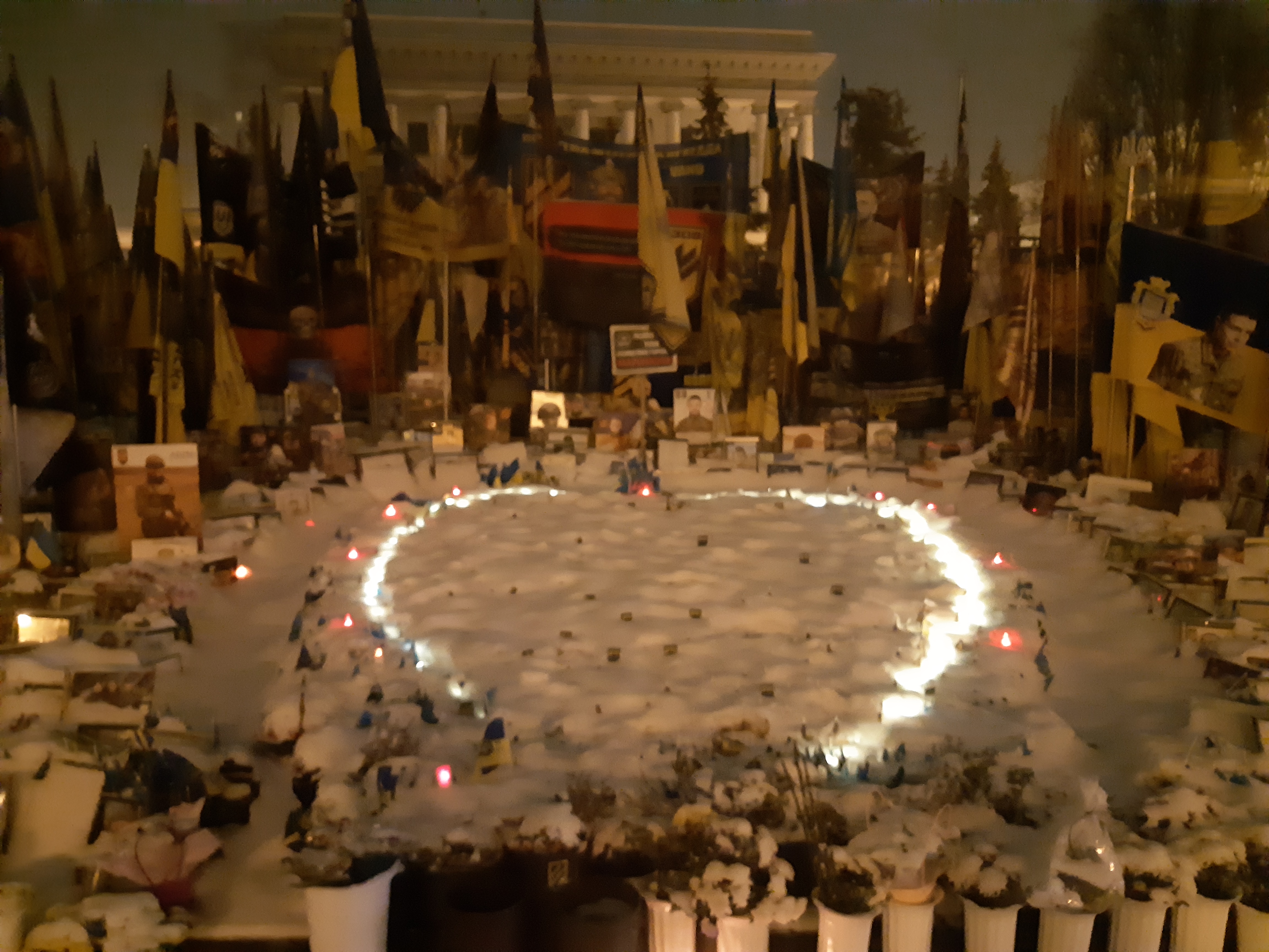 Winter evening view of the Maidan memorial to fallen Ukrainian defenders - flags, portraits and candles arranged in a heart in the snow. Editor's own photo.