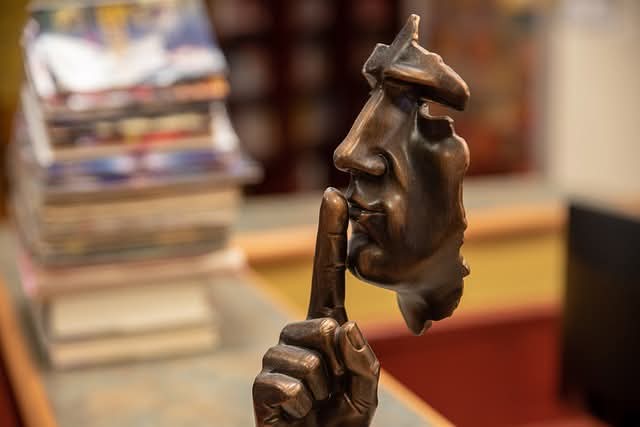 A sculpture of a face with a finger to its lips