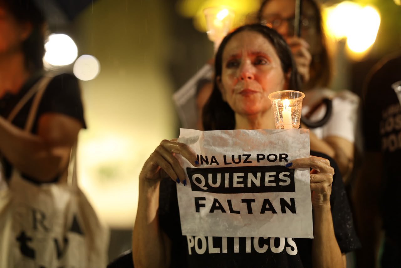 A woman holds a candle and a sign for the missing