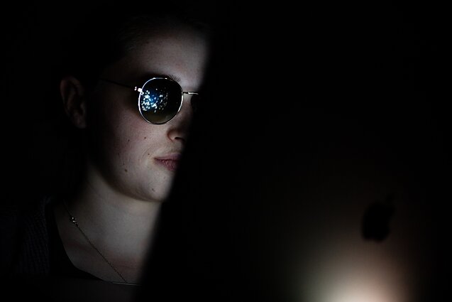 A teenager with a screen reflected in his glasses
